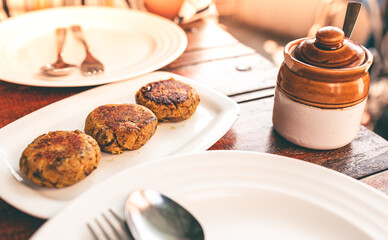 Freshly prepared veg patty served at an outdoor restaurant table. Indian food Aloo Tikki in a white plate ready to eat. Simple lunch meal on a dining table.