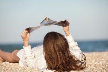 Woman reading magazine on beach