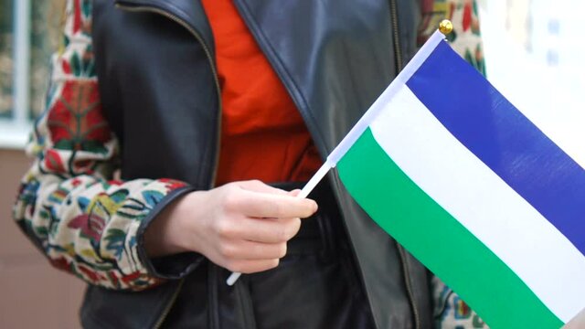 Unrecognizable woman holding Molossian flag. Girl walking down street with national flag of Molossia.