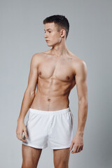 athlete with pumped up abs looking to the side cropped view gray background