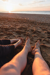 couple sitting on sandy beach looking on sunset