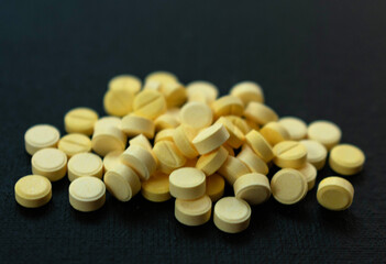 Yellow and small pills on a black background.
Close-up.