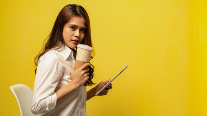 Women playing tablet while drink coffee with yellow background