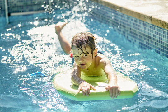 Adorable child learning to swim in outdoor pool