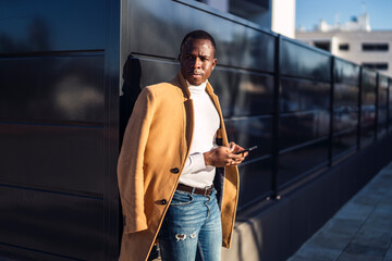 Concentrated black man using smartphone while standing on street