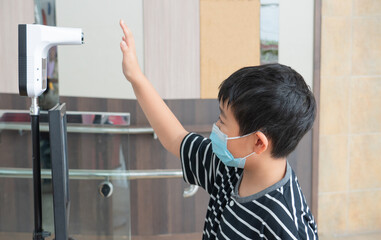 Fototapeta na wymiar One Asian boy is checking the temperature at the entrance by raising his palm up.The student and the fever scanning during COVID-19 concept.