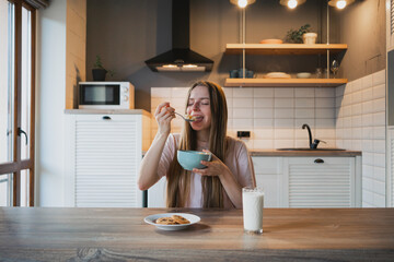 Woman eating delicious cereal for breakfast at home