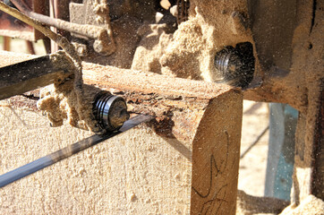 sawing a log with a band saw. wet sawdust. the roller pulls the saw band.