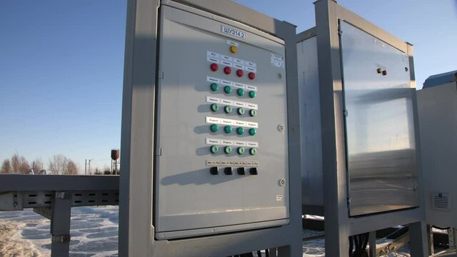 Control panel with colorful buttons near reservoirs at wastewater treatment station on sunny winter day extreme close view
