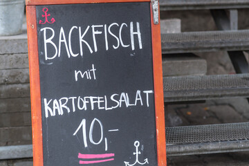 Restaurant menu board offering Backfisch mit Kartoffelsalat, German for Fried fish with potato salad