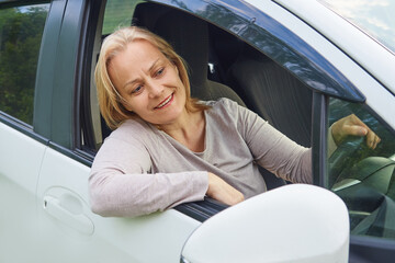 Senior woman driver sitting inside the car, looking out the window