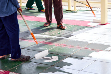 worker painting white color on the floor by roller paint