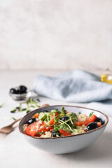 Bowl with couscous and vegetables on light background