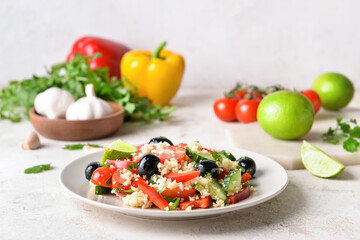 Plate with couscous and vegetables on light background