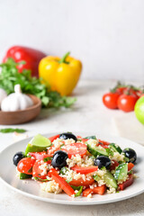 Plate with couscous and vegetables on light background