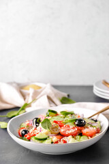 Bowl with couscous and vegetables on light background