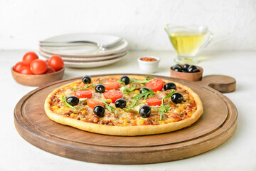 Board with tasty pizza on light background