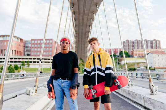 Two handsome teenage boys with skateboard standing on the bridge