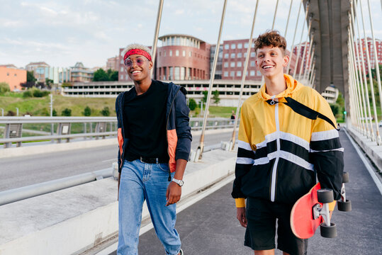 Two handsome teenage boys with skateboard standing on the bridge