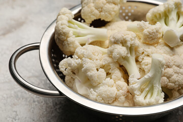 Colander with cauliflower cabbage on grunge background, closeup