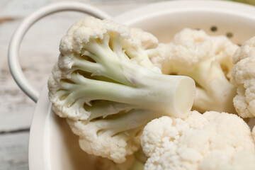 Colander with cauliflower cabbage on wooden background, closeup