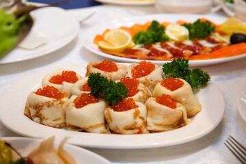 Pancakes with red caviar close-up. Buffet table with seafood, snack delicacy. Salmon roe on the table. Seafood in the restaurant, a healthy snack.