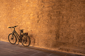 Fototapeta na wymiar Racing bicycle leaning against textured wall in the evening golden sunlight