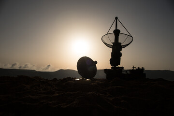 Space radar antenna on sunset. Silhouettes of satellite dishes or radio antennas against night sky....