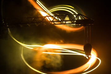 Abstract Industrial background with construction crane silhouette over amazing night sky with fog and backlight. Tower crane against the foggy sky at night.