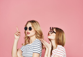 Obraz premium two girlfriends striped t-shirts with sunglasses pink background