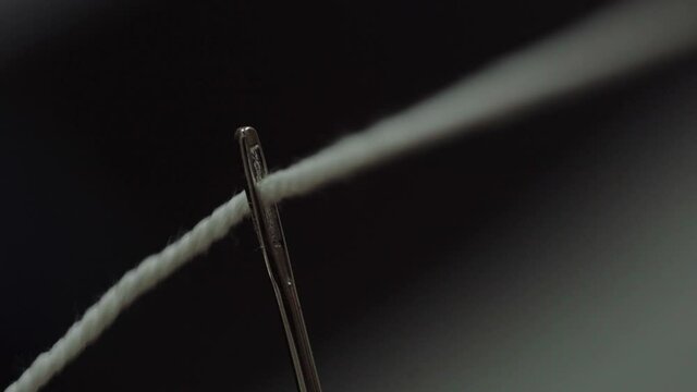 Closeup shot of a thread that is threaded through the eye of a needle
