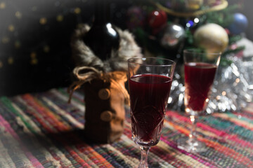 Red wine in crystal glass with bottle on colorful carpet with creative New Year artwork decorations. Copy space