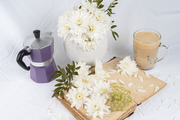 Still life with an old book, a cup of coffee and chrysanthemum flowers