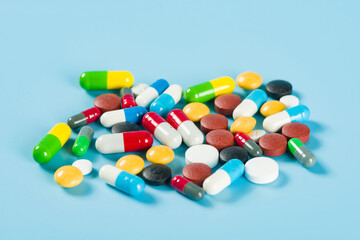 Assorted pharmaceutical medicine pills, tablets and capsules on blue background