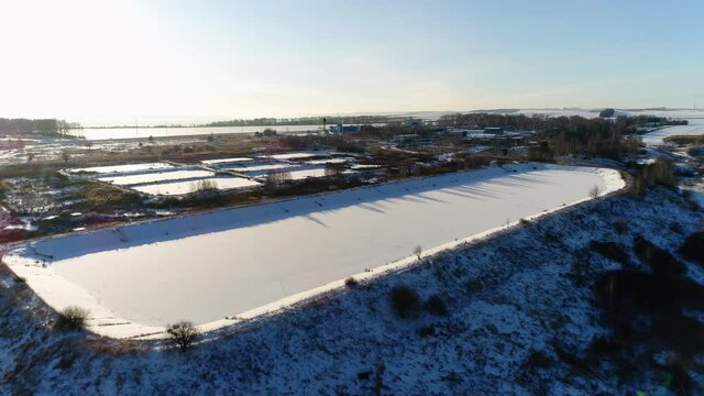 Large pool and basins at contemporary filtration station on snowy hill at sunset in winter evening bird eye view
