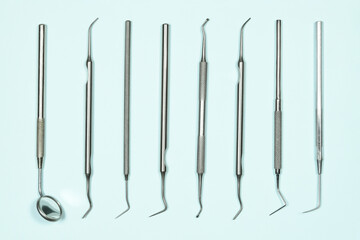Some medical dental tools on light blue background. Flat lay closeup top view on dental instruments. Dental probes and explorers with mirror