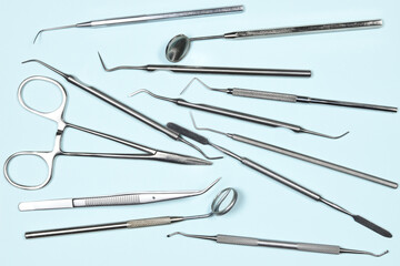 Medical dental instruments on light blue background. Flat lay close up top view on dental tools. Tooth care, dental hygiene and health concept.