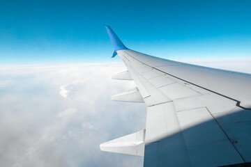 A wing of a modern passenger airplane above the clouds. International cargo transportation, air travel, transport. Copy space.