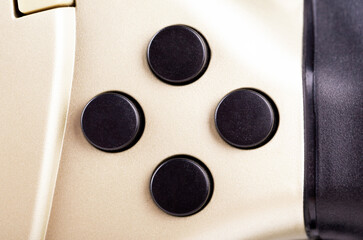 Four round blank, empty buttons on a simple game controller, object detail, extreme closeup, front view, from above, nobody. Classic retro vintage arcade gaming controllers, accessories concept