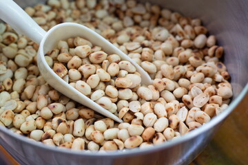 Roasted peanuts on a scoop in bowl.