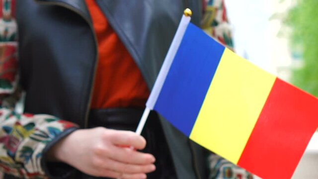 Unrecognizable woman holding Romanian flag. Girl walking down street with national flag of Romania