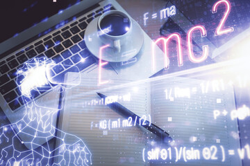 Physics and math theme hologram with formula drawings over computer on the desktop background. Top...