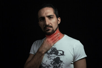 Sore throat. A man holding on to a sore throat on a black background.