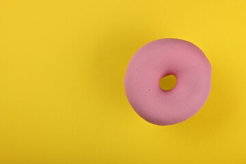 One pink glazed donut over yellow