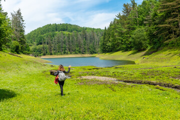 A young woman walking through the Domiko reservoir, a lake with pine trees around it and beautiful spring flowers. A reservoir in Navarra next to Lesaka
