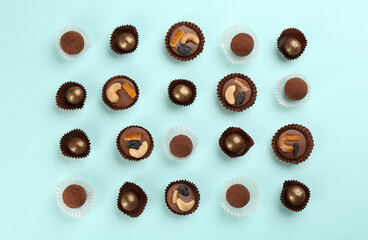 Different delicious chocolate candies on light blue background, flat lay