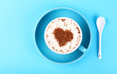 Full cup of latte cappuccino coffee on blue paper