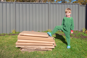 Little boy standing next to a pile of crushed cartons ready for recycling
