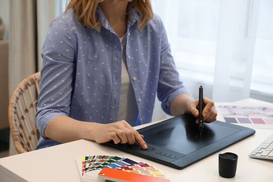 Professional designer with graphic tablet at table indoors, closeup