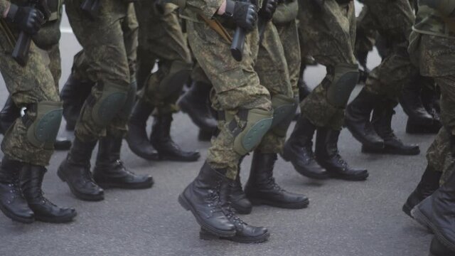 Soldiers march on the spot during demonstrations or military parades. Close-up of legs in army boots and knee pads.